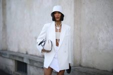 With crop top, necklace, white long blazer, black and white bag and white wrap mini skirt