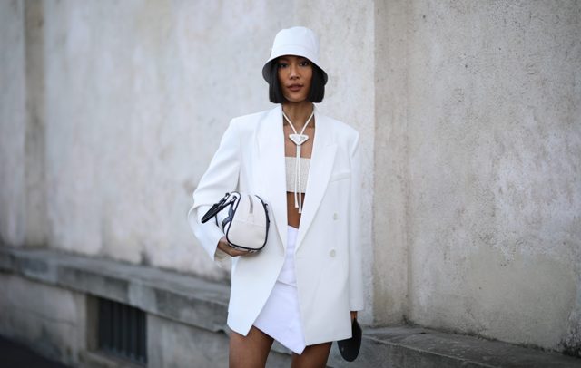 With crop top, necklace, white long blazer, black and white bag and white wrap mini skirt