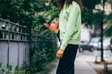 With light green loose sweatshirt, black bag, navy blue loose jeans and colorful sneakers