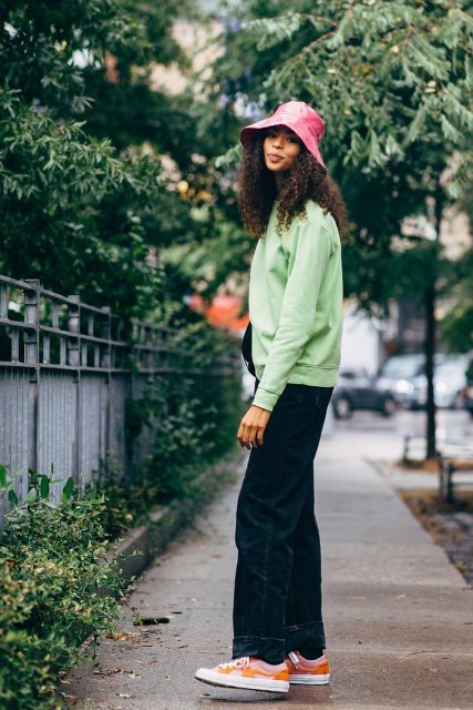 With light green loose sweatshirt, black bag, navy blue loose jeans and colorful sneakers