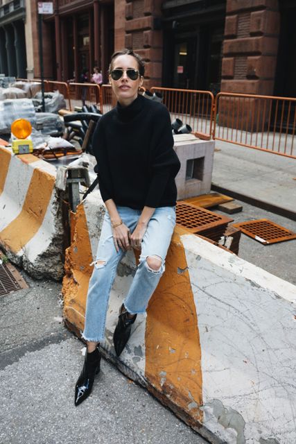With sunglasses, black loose turtleneck and light blue distressed jeans