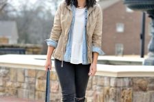 With white ruffled loose blouse, light blue denim button down shirt, beige jacket, dark gray distressed skinny jeans, white lace up shoes and blue leather tote bag