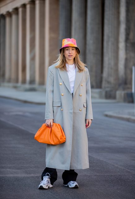 With white t-shirt, gray maxi coat, orange clutch and black long pants