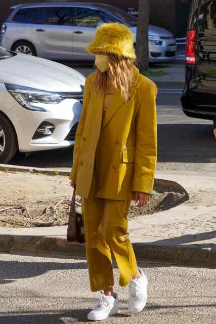With yellow shirt, mustard yellow oversized blazer, cropped trousers, white sneakers and brown bag