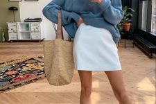 a blue oversized sweater, a white mini skirt, tan sandals and a woven tote for a girlish look