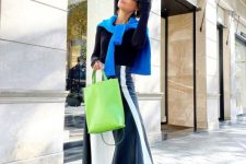 a bold spring look with a black long sleeve top, a blue sweater on top, a striped black and white midi, white sneakers and blue socks plus a neon green bag