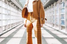 a bold spring outfit with a white turtleneck, mustard checked trousers, a mustard cropped jacket, white boots