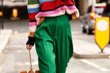 a  colorful spring look with green high waisted pants, a colorful striped sweater, a yellow bag and neutral shoes