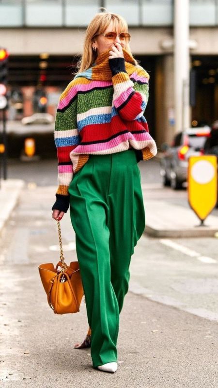 a  colorful spring look with green high waisted pants, a colorful striped sweater, a yellow bag and neutral shoes