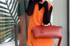 a colorful spring outfit with a black long sleeve top, an orange waistcoat, orange trousers, a red handbag is amazing