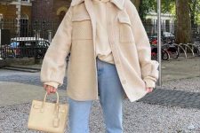 a neutral and cozy spring outfit with a hoodie, a shirt jacket, light blue jeans, tan boots and a creamy bag