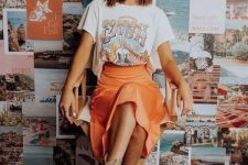 a printed t-shirt, an orange slip midi skirt, snakeskin print boots and a camel hat plus statement earrings