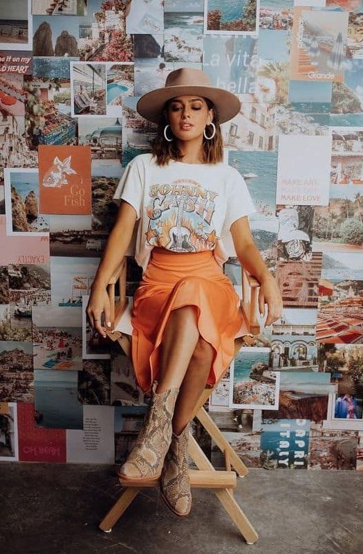 a printed t-shirt, an orange slip midi skirt, snakeskin print boots and a camel hat plus statement earrings