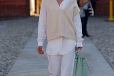 a white oversized shirt, white pants, a creamy knit waistcoat, white trainers and a light green bag for maximal comfort