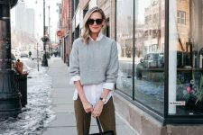 a white shirt, a grey jumper over it, olive green cropped pants, tan shoes and a black shopper bag