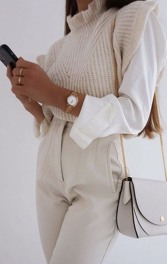 a white shirt, a woven waistcoat with ruffle sleeves, creamy high waisted pants, a grey bag and cool rings