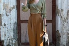 an olive green puff sleeve crop top, rust-colored high waisted trousers, white high top sneakers and a white bag
