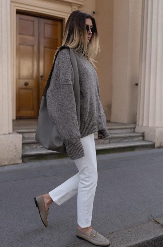 an oversized grey sweater, white jeans, grey loafers and a large grey bag