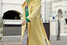 grey trousers, a bright green hoodie, a yellow trench, white high top sneakers and statement sunglasses