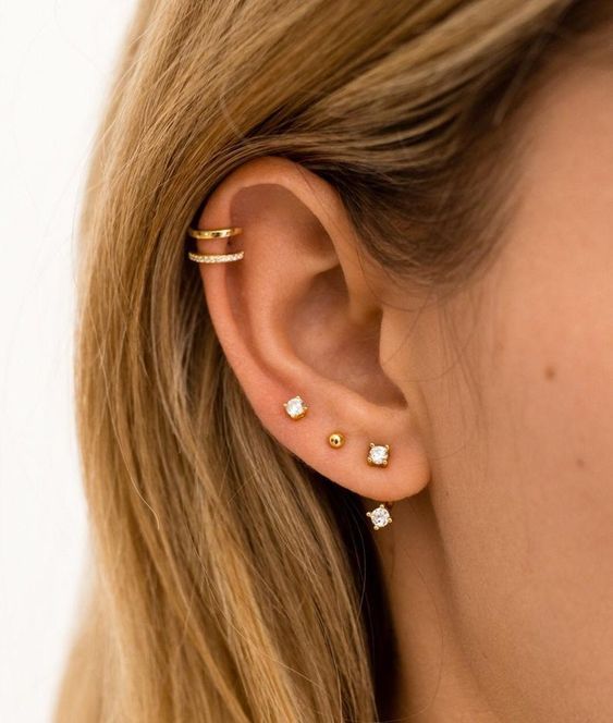 a chic and modern ear look done with a triple lobe piercing and a double helix piercing, with gold studs and hoops