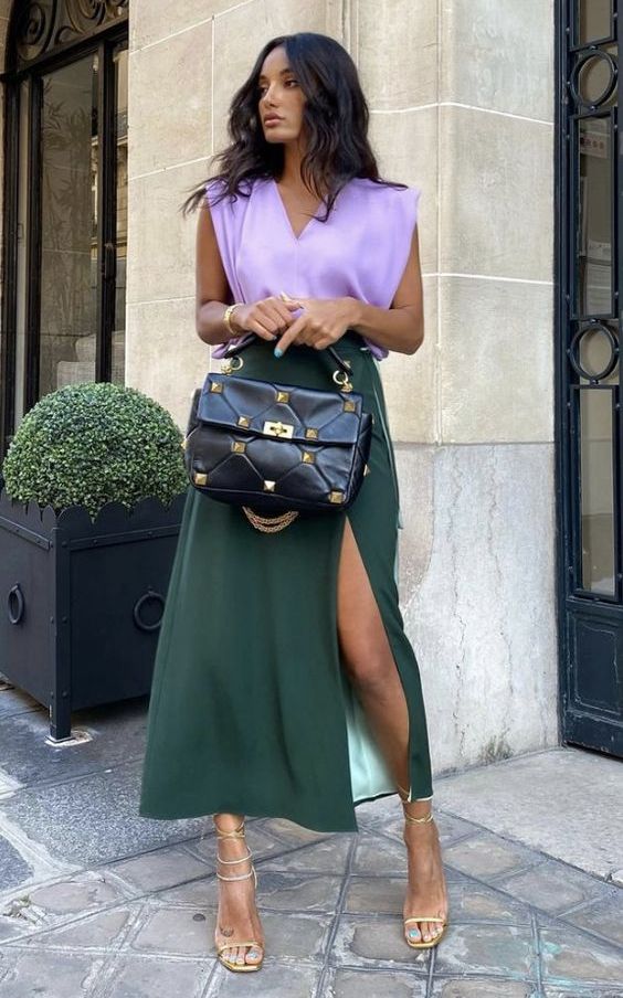 a bold work outfit with a Very Peri sleeveless top, a dark green midi skirt with a slit, gold shoes and a black bag