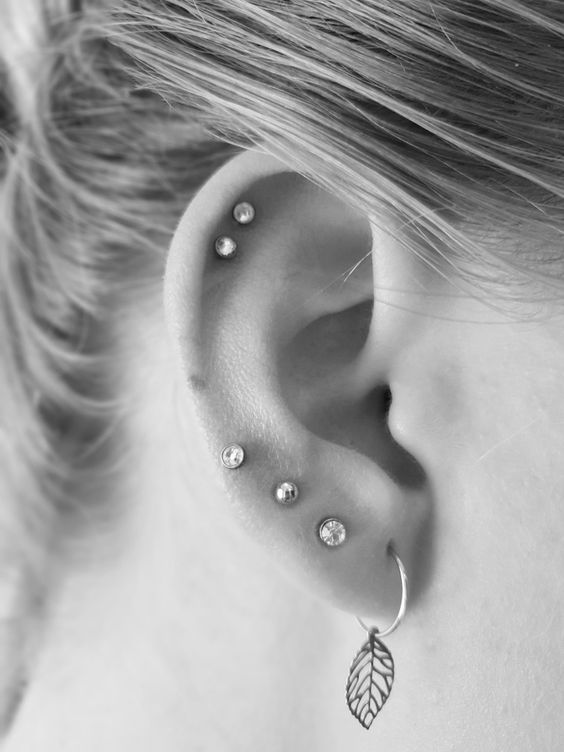 a double helix piercing done with elegant studs and four piercings in the lobe finished off with studs and an airy earring