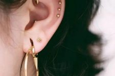 03 a double lobe, a rook, a triple helix, a conch piercing done with statement gold hoops and beautiful gold studs for a stylisha nd edgy look