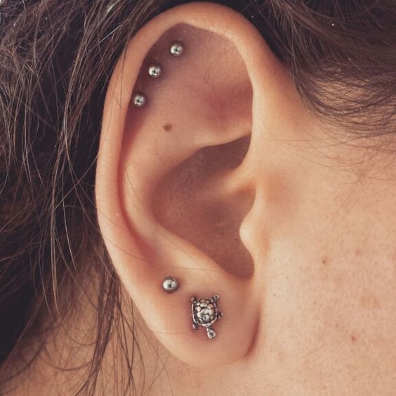 a delicately curated ear with a double lobe peircing with a couple of pretty studs, a triple helix piercing with matching studs