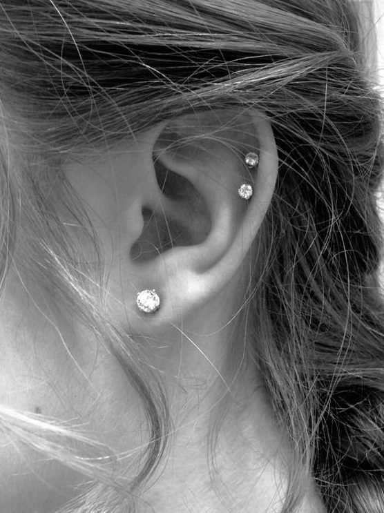 a lobe piercing and a double helix piercing accented with matching shiny studs look chic