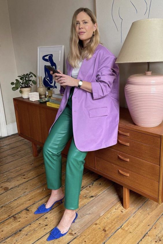 a bright work outfit with a white t shirt, emerald leather pants, a Very Peri oversized blazer, electric blue mules is bold