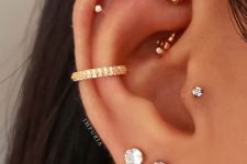 06 a refined and glam look with a double lobe piercing with chain, a conch piercing with a gold hoop, a tragus and a triple helix piercing with studs and a rook piercing