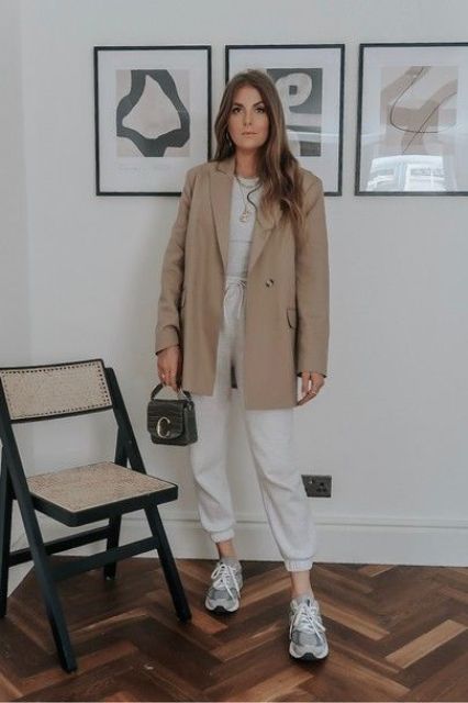 a simple and trendy look with a grey t-shirt, neutral sweatpants, grey trainers, a tan oversized blazer and a grey bag