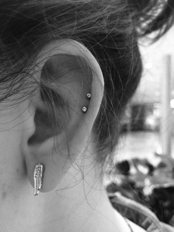 a stylish ear look with a double helix piercing with studs and a beautiful wing earring in the lobe