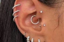 08 glam ear styling with stacked lobe and helix and flat piercings, a tragus, a forward helix and a daith piercing