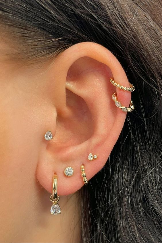 beautiful and glam ear styling with multiple lobe peircings, a tragus piercing and a double helix one, all done with gold hoops and studs