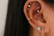 10 glam and chic ear styling with a double lobe piercing, a triple helix piercing, a rook, a tragus and a conch, all done with studs and pretty hoops