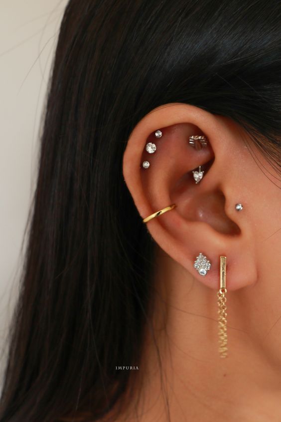 glam and chic ear styling with a double lobe piercing, a triple helix piercing, a rook, a tragus and a conch, all done with studs and pretty hoops