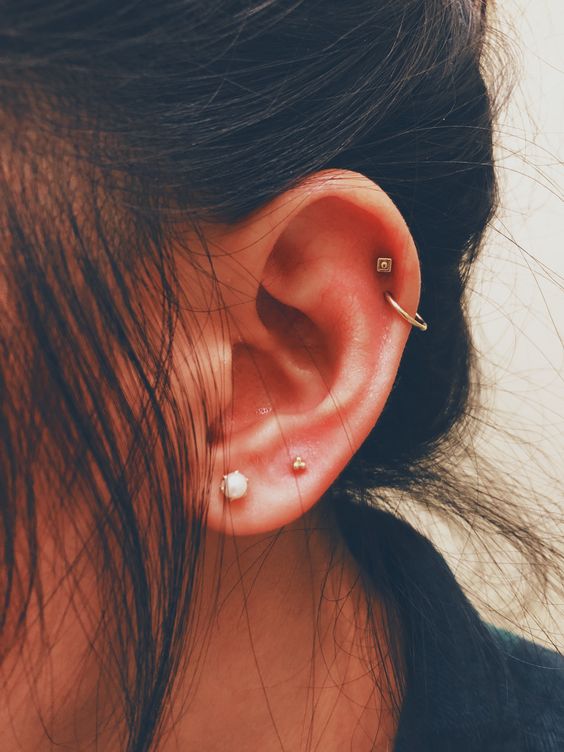 bold and catchy ear styling with a double lobe piercing and a double helix piercing with various studs and a hoop