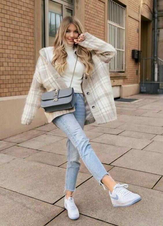 a white turtleneck, blue cropped jeans, white and blue trainers, a tan and white checked shaket, a dusty blue crossbody bag
