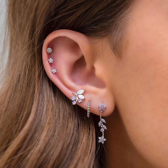 refined ear styling with a triple lobe peircing with beautiful floral earrings, a triple helix piercing with lovely studs