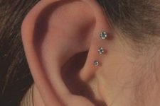 15 a delicate triple forward helix piercing done with pretty studs, a double lobe piercing with matching studs for a chic and beautiful ear look