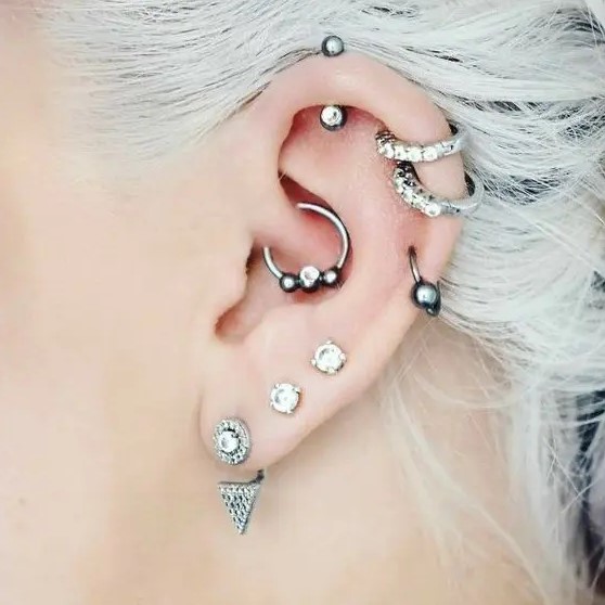 bold ear styling with stacked helix piercings and stacked lobe ones, with a daith piercing all done with cool hoops and studs