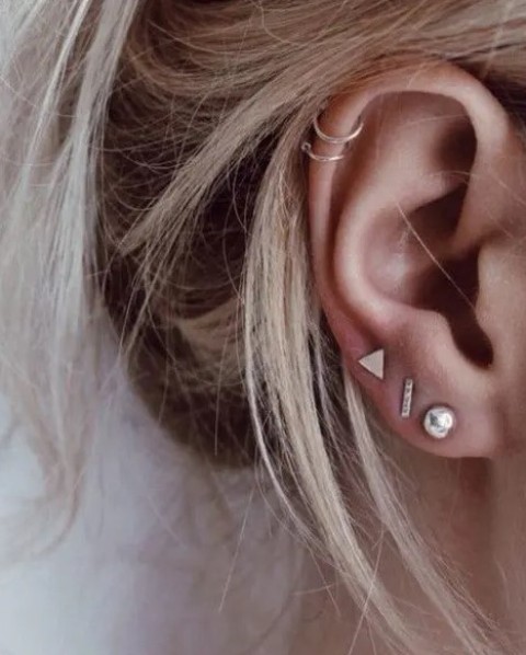 minimalist styling with two helix piercings done with little hoops and three lobe piercings done with gold studs