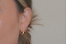 16 modern and glam ear styling with gold hoop earrings in the lobe and a double helix piercing done with pretty studs