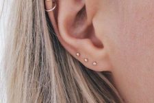 17 stacked lobe piercings with minimalist gold stud earrings and stacked helix piercings with hoop earrings