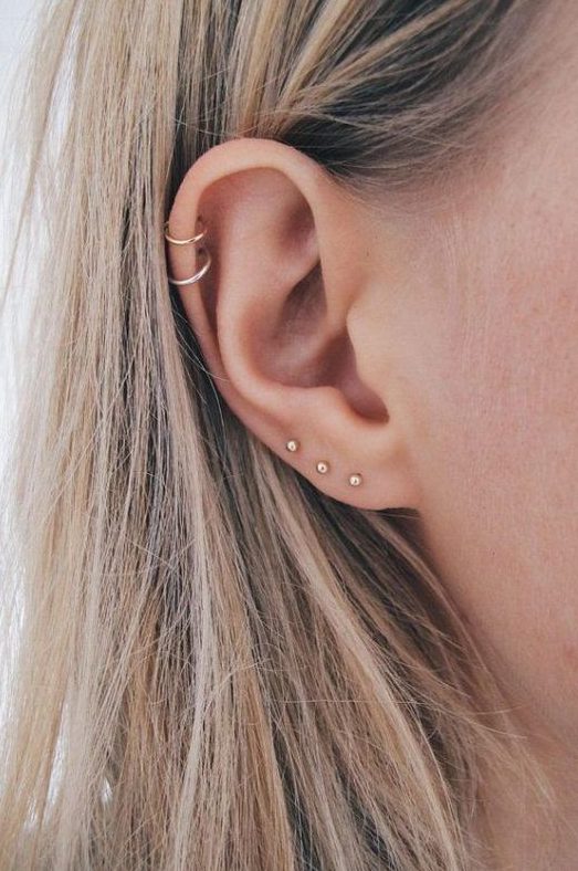 stacked lobe piercings with minimalist gold stud earrings and stacked helix piercings with hoop earrings