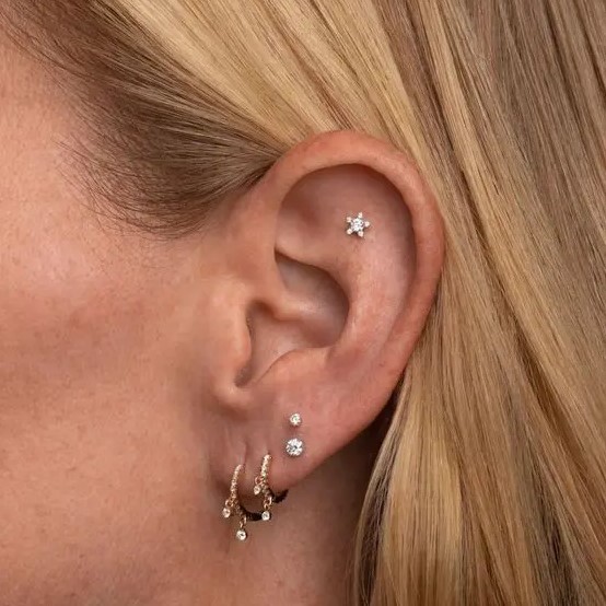 a cool stacked lobe piercing with gold hoops and studs plus a single flat piercing with a star stud for a dreamer