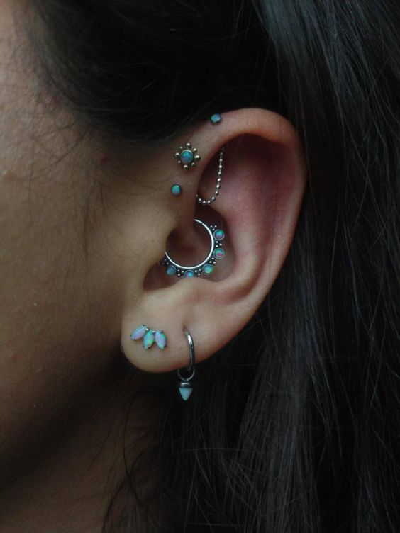 beautiful opal ear styling with a double lobe piercing, a daith piercing, a triple forward helix one, all done with matching studs and hoops