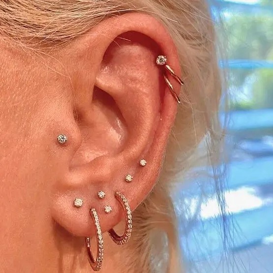 bold and glam ear styling with multiple lobe piercings, a helix and a tragus one done with rhinestone studs and hoops