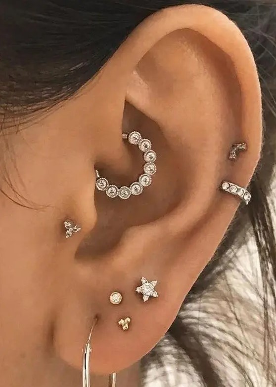 chic and glam ear styling with a stacked lobe piercing, two helix, a tragus and a daith one done with shiny rhinestone studs and hoops